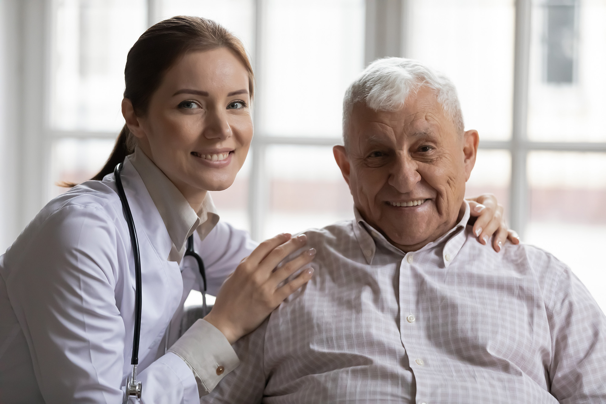 Portrait of smiling female nurse posing with elderly male patient