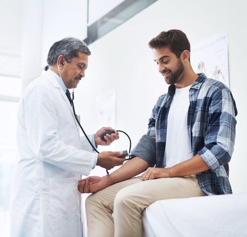 Healthcare, patient and doctor with blood pressure test, help and wellness checkup of person at hospital. Medicine, health care expert and Indian man in doctors office consulting medical professional